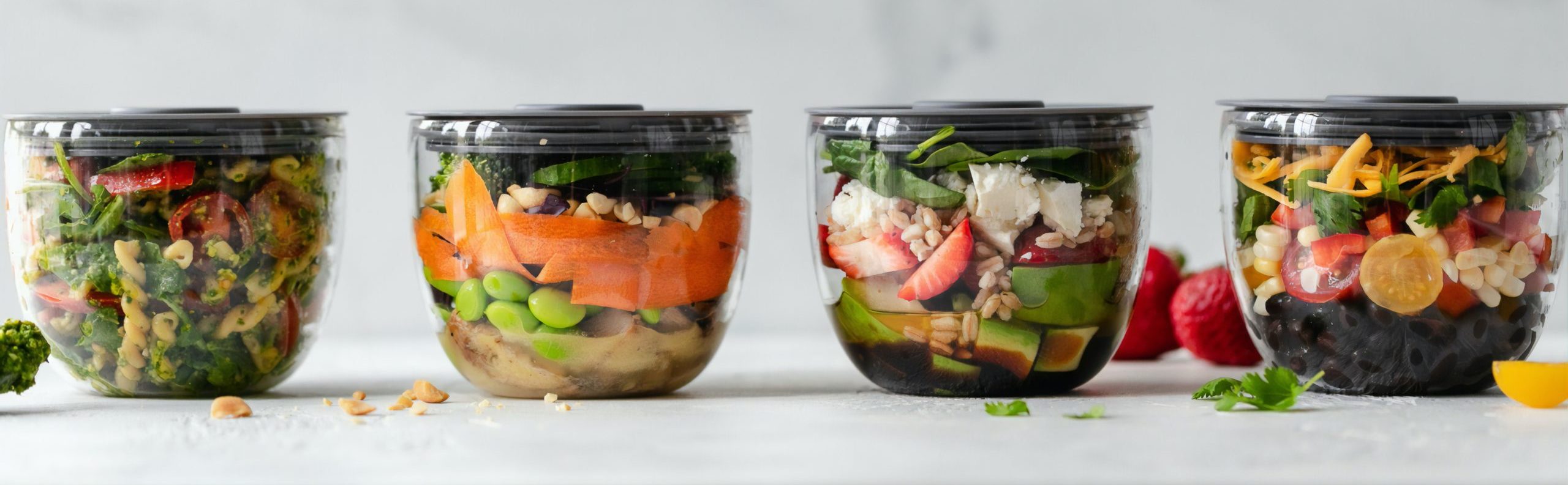 four clear plastic bowls with vegetables