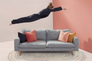 woman jumping in gray 2-seat sofa